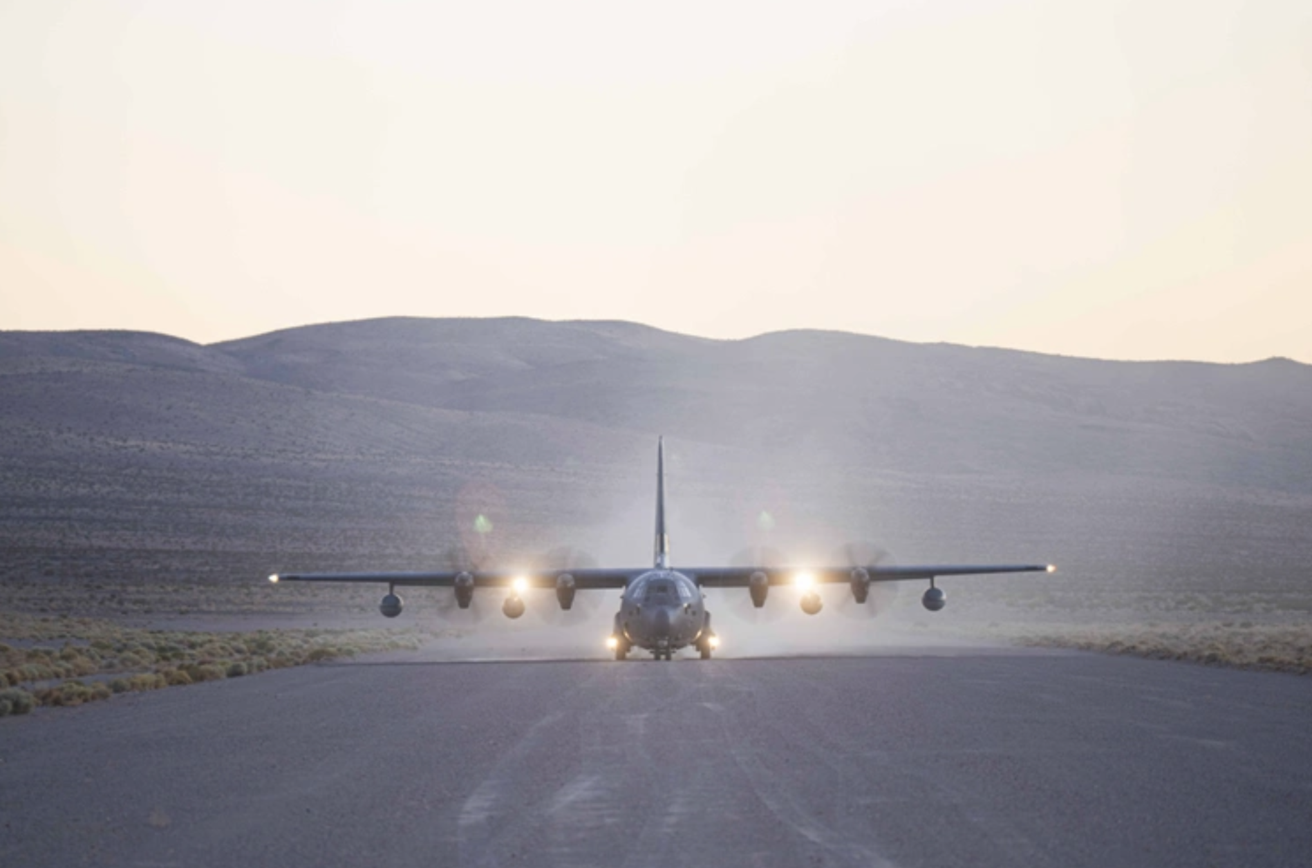 Military transport aircraft on a desert runway at dawn